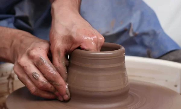 Pottery class in Manchester: Potter throwing a clay pot on a potter's wheel.